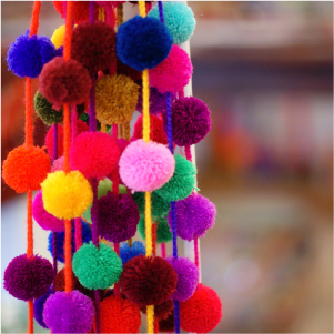Photo of strings of colorful pom poms Zinnia Folk Arts