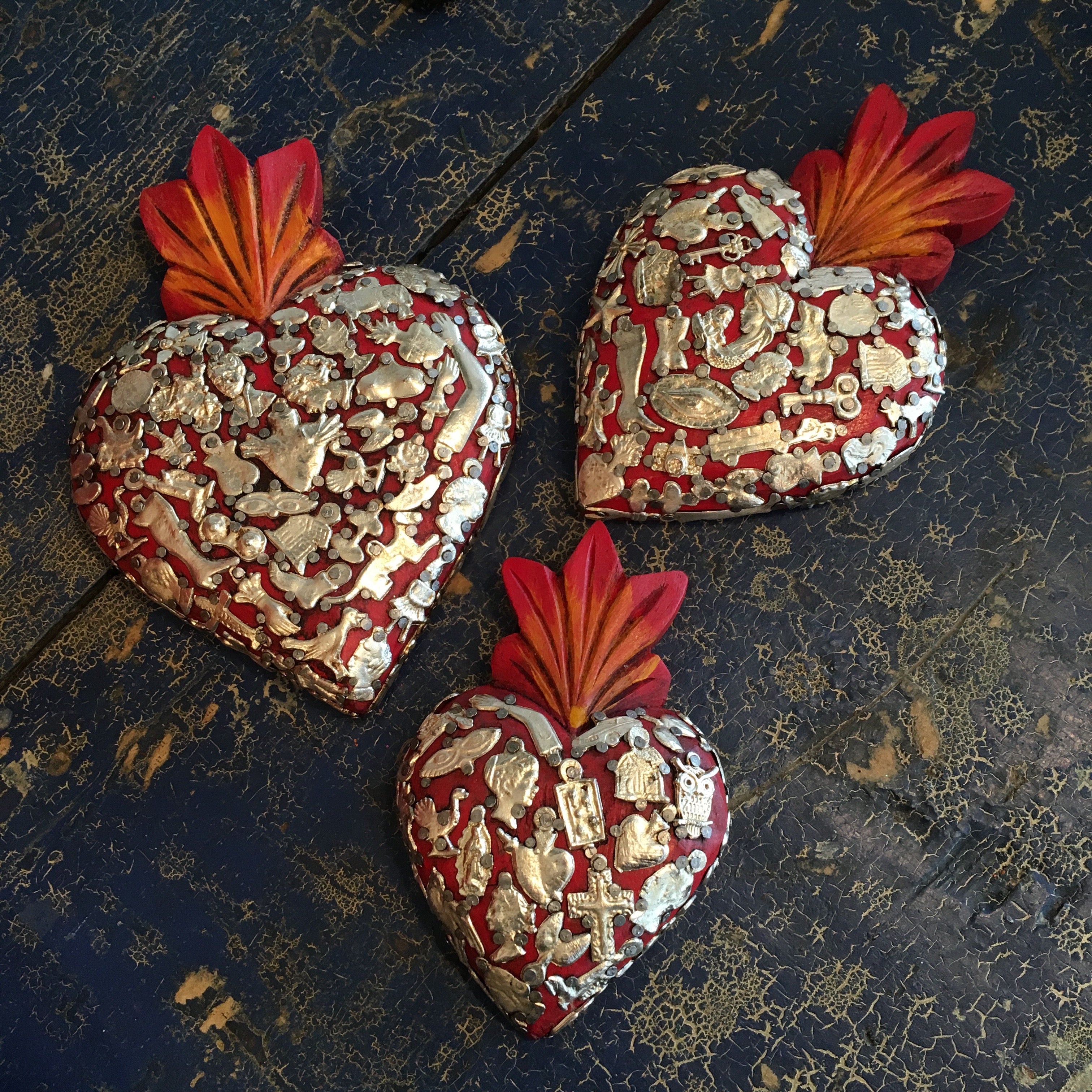 Photo of red sacred hearts covered with small milagros Zinnia Folk Arts